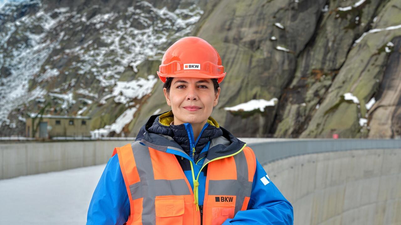 BKW-Symbolbild: Mitarbeiterin mit Helm und oranger Weste blickt in die Kamera.