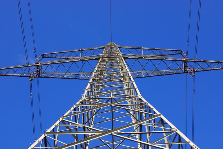 Strommast von unten in Richtung blauer Himmel fotografiert